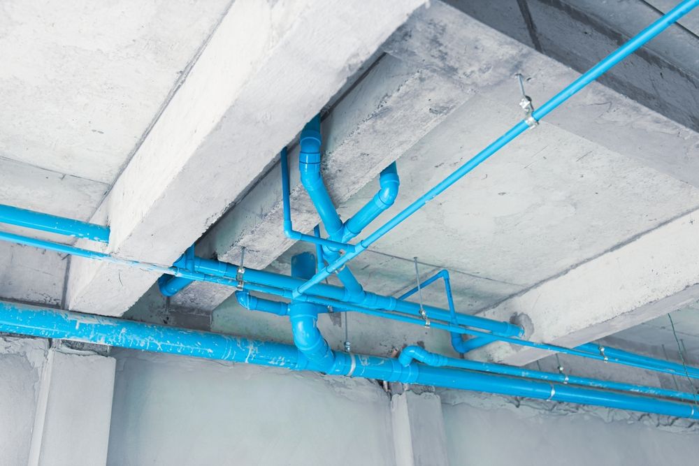 Network of blue PVC pipes and fittings under a concrete ceiling